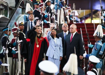 Cuatro autoridades venezolanas saludan desde unas escaleras flanqueadas por militares uniformados con fusiles