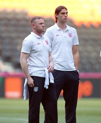 Wayne Rooney y Andy Carroll de pie en un campo de fútbol con la vestimenta de la selección inglesa