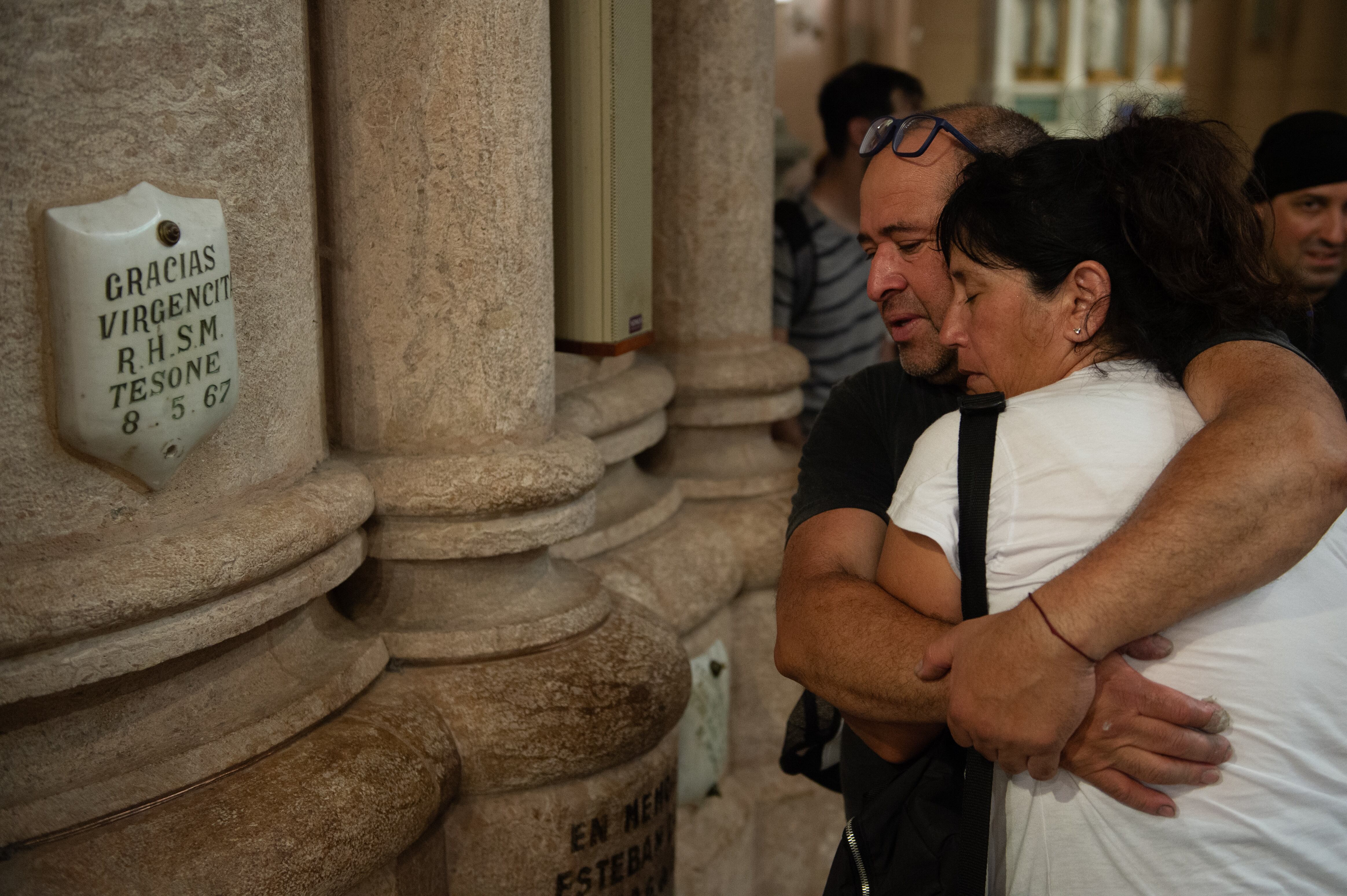 Una pareja se abraza en silencio al entrar a la Basílica de Luján después de caminar 60 kilómetros desde Liniers