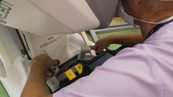 Un médico con mascarilla manipula los mandos de una consola médica con la inscripción Medbot y botones amarillos con las letras L y R