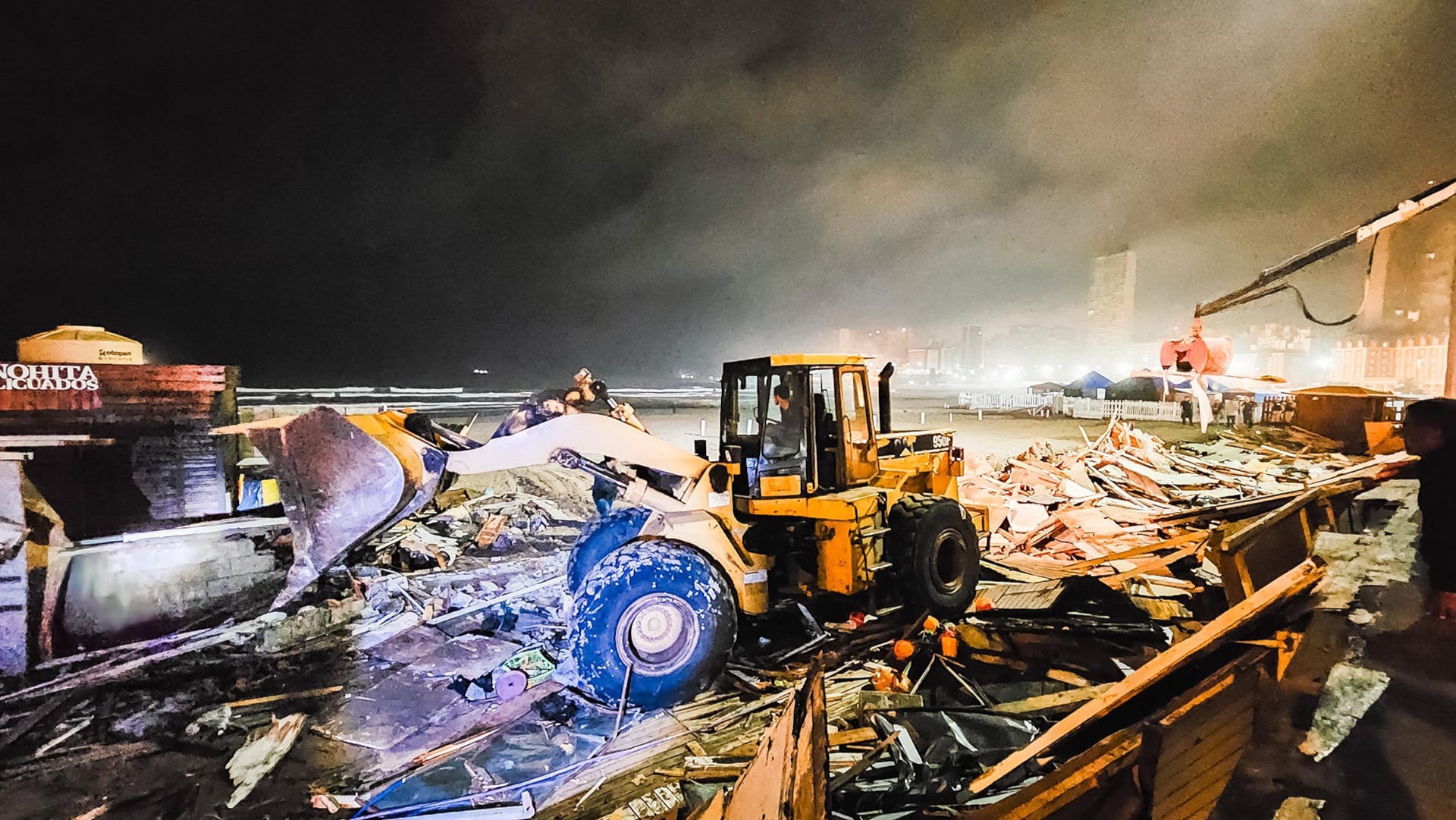 Una cargadora frontal trabaja durante el operativo de desalojo de la feria La Bristol en la playa de Mar del Plata, Argentina, bajo la luz de la noche.