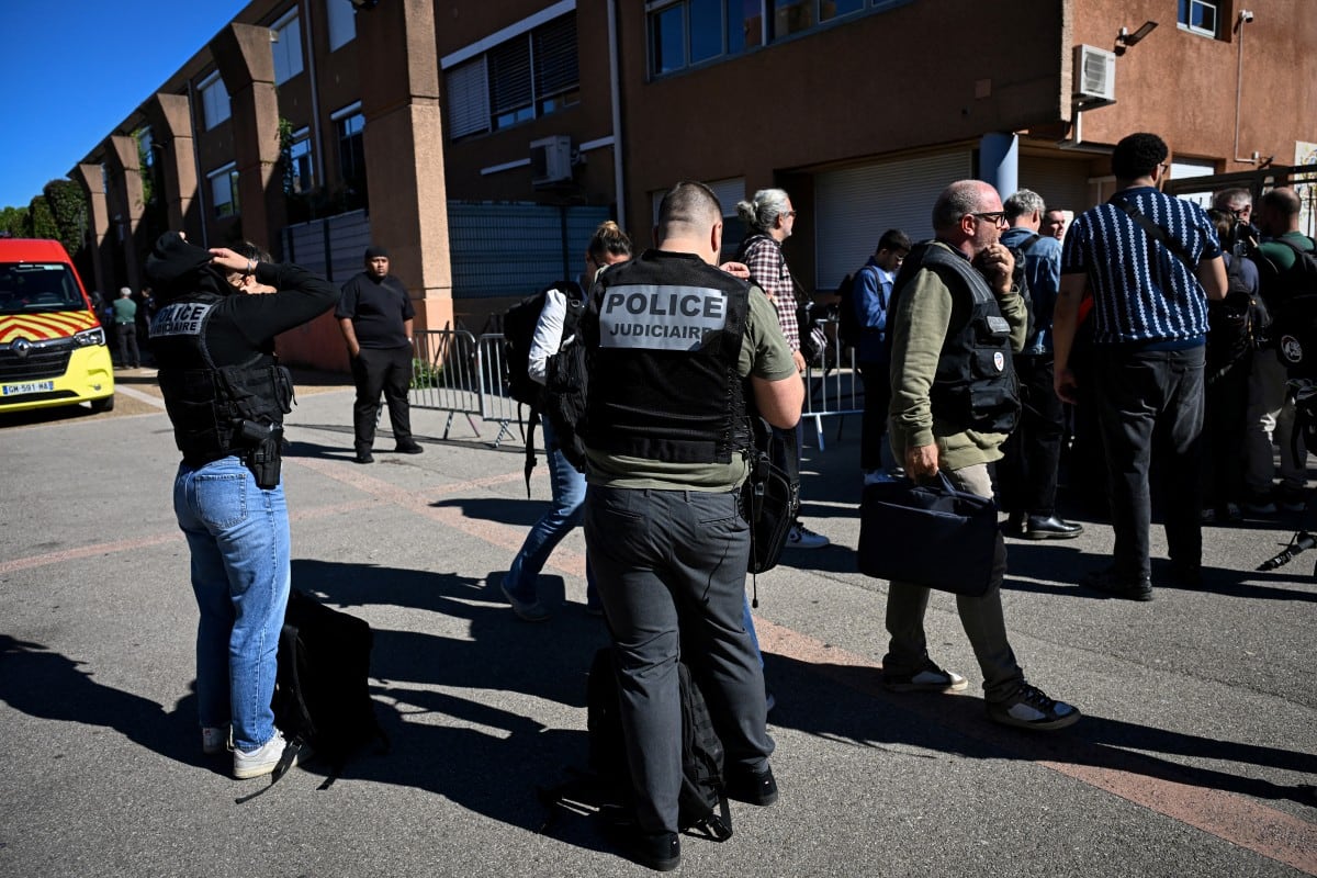 Varias personas y agentes de la policía judicial se concentran frente a la escuela secundaria Joseph-Lakanal tras un tiroteo ocurrido en Aubagne, Francia. (Miguel Medina/AFP)
