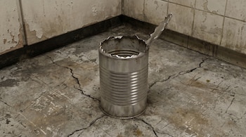 Primer plano de animación 3D: Lata de leche de metal vacía con borde afilado en un suelo de cemento agrietado y paredes deterioradas en una cocina.