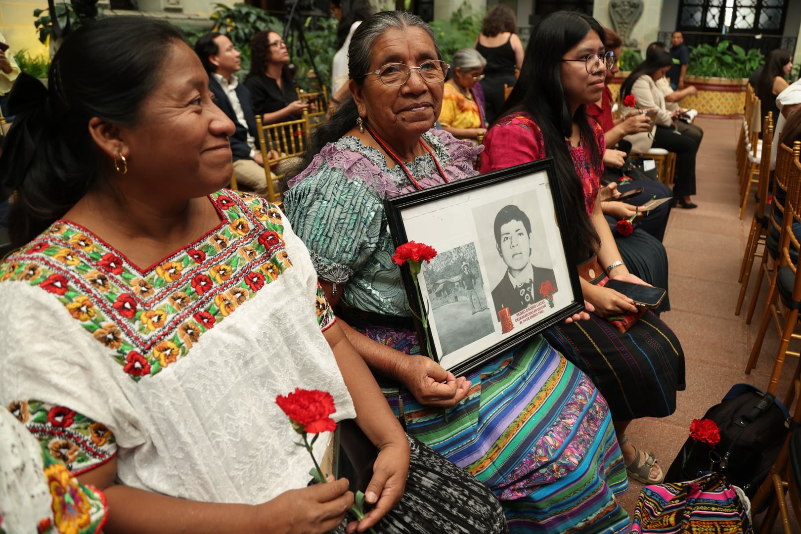 AME2443. CIUDAD DE GUATEMALA (GUATEMALA), 19/06/2026.- Francisca Osorio (c) sostiene una fotografía de sus dos hermanos desaparecidos durante un acto conmemorativo este viernes, en Ciudad de Guatemala (Guatemala). En el marco del día Nacional contra la Desaparición Forzada en Guatemala, que se conmemora cada 21 de junio, se realizó el lanzamiento del mecanismo de búsqueda humanitaria de personas desaparecidas durante el conflicto armado interno en Guatemala 2026-2036, en el Palacio Nacional de la Cultura en Ciudad de Guatemala. EFE/ Mariano Macz
