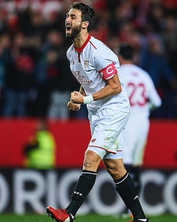 El futbolista Nicolás Pareja grita con el puño cerrado, viste el uniforme blanco del Sevilla FC y lleva un brazalete de capitán