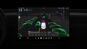 Pantalla digital de un automóvil que muestra una figura de fantasma blanca rodeada de autos verdes y siluetas de esqueletos en un mapa