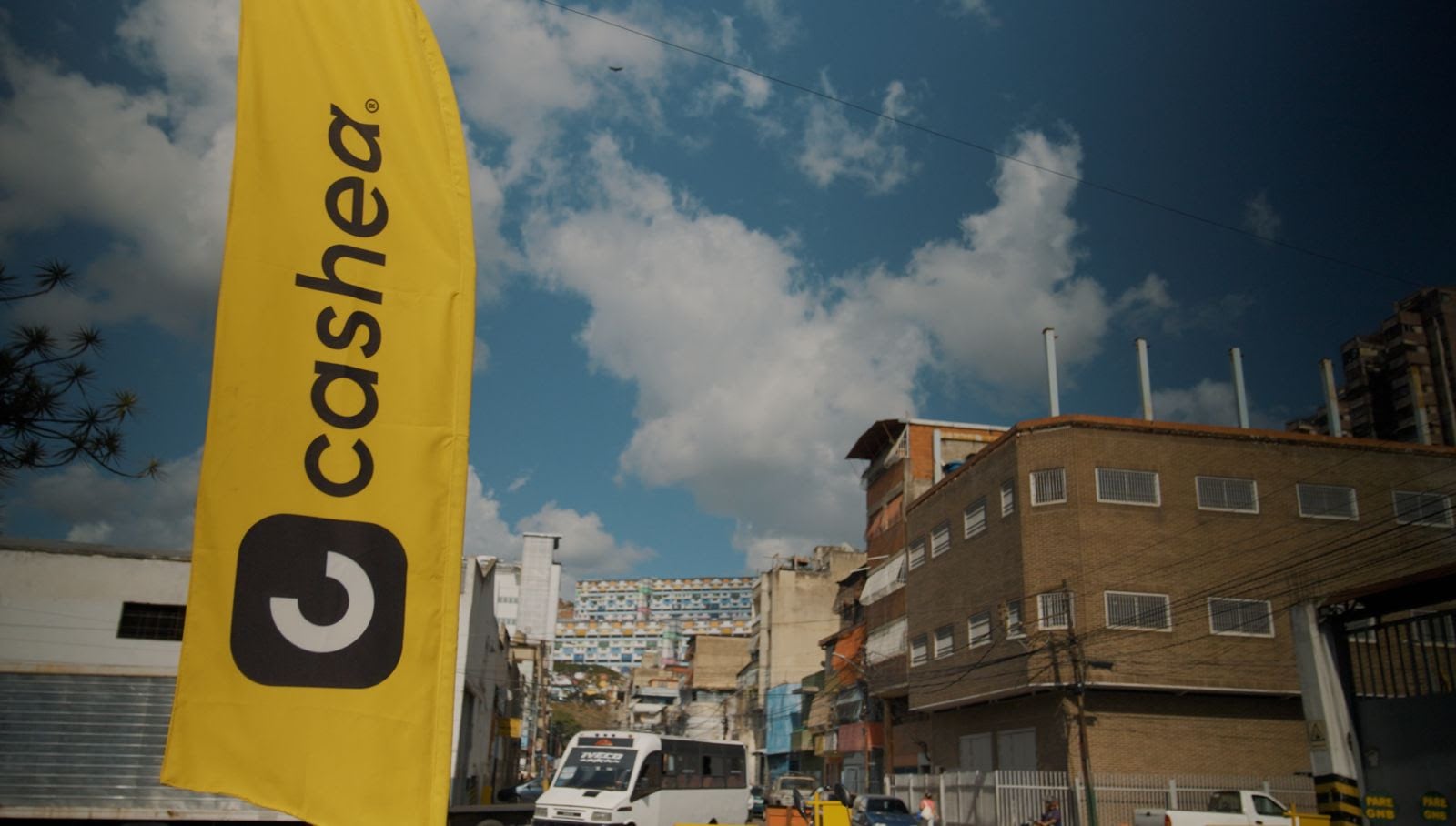 Una bandera amarilla con el logotipo y el nombre de Cashea se alza en un área urbana de Venezuela (Endeavor)