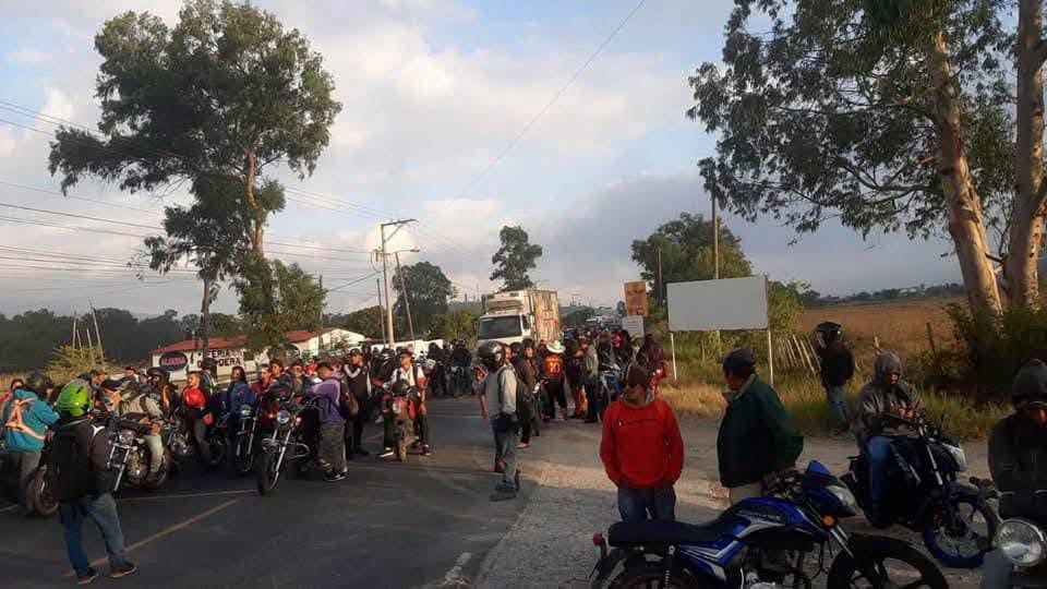 Un grupo de motociclistas y peatones se concentra sobre la cinta asfáltica en una zona arbolada junto a un camión de carga. (Redes Sociales)