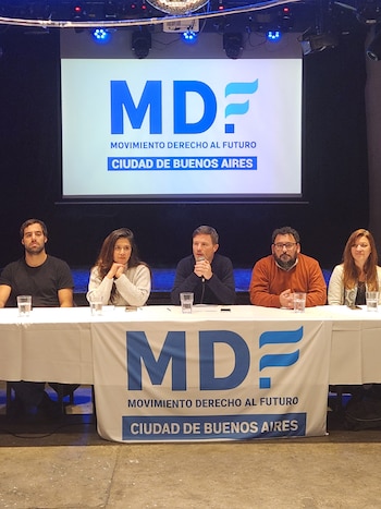 Cinco personas sentadas tras una mesa blanca. Detrás hay una pantalla y en la mesa un cartel con el logo MDF y texto "Movimiento Derecho al Futuro Ciudad de Buenos Aires"