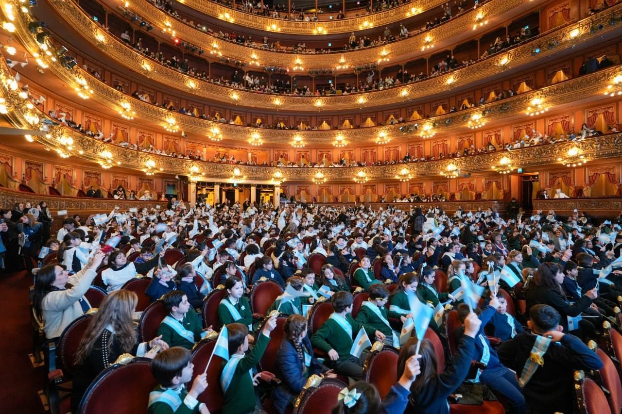 Una multitud de niños y niñas agita banderas argentinas en el Teatro Colón