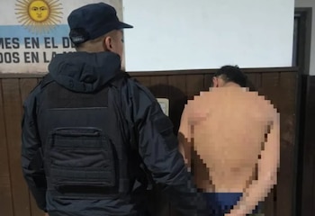 Un agente de policía visto de espaldas, un hombre arrestado de espaldas con el cuerpo pixelado, y una bandera con un sol en el fondo
