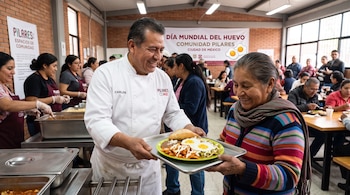 Un cocinero entrega un plato con huevos y chilaquiles a una mujer frente a una manta que dice Día Mundial del Huevo en la Ciudad de México