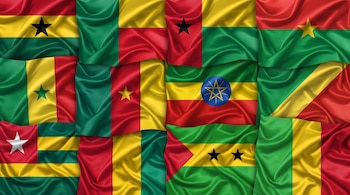 Múltiples banderas de varios países apiladas con diseños que incluyen los colores verde, amarillo y rojo, estrellas y un emblema circular.