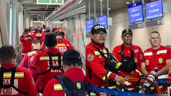 Equipo de rescatistas USAR Perú en uniforme rojo transita por una pasarela y una terminal de aeropuerto con pantallas de información de vuelos