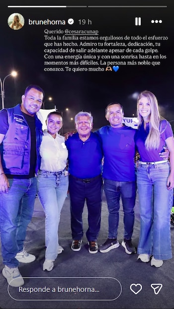 Cinco personas sonrientes, incluyendo a Brunella Horna y César Acuña en el centro, posan de pie en un evento nocturno con luces de fondo
