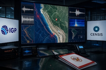 Monitores con un mapa de Perú, gráficos de ondas sísmicas y logotipos institucionales junto a una carpeta con un escudo sobre la mesa.