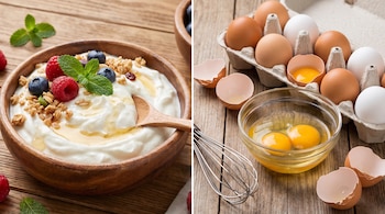 Bol de yogur griego con arándanos, frambuesas, granola, miel y menta; cartón de huevos blancos y marrones, dos yemas en un recipiente de cristal, cáscaras y batidor.