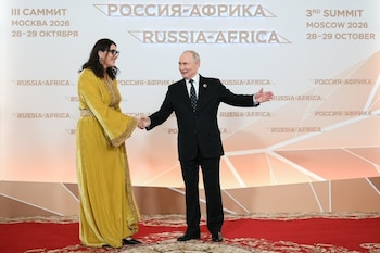 Vladimir Putin estrecha la mano de Fatima Zahra Mansouri ante un panel con la inscripción de la cumbre Rusia-África sobre una alfombra roja