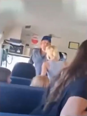 Vista del interior de un autobús escolar donde una mujer de cabello claro habla con el conductor en la parte delantera