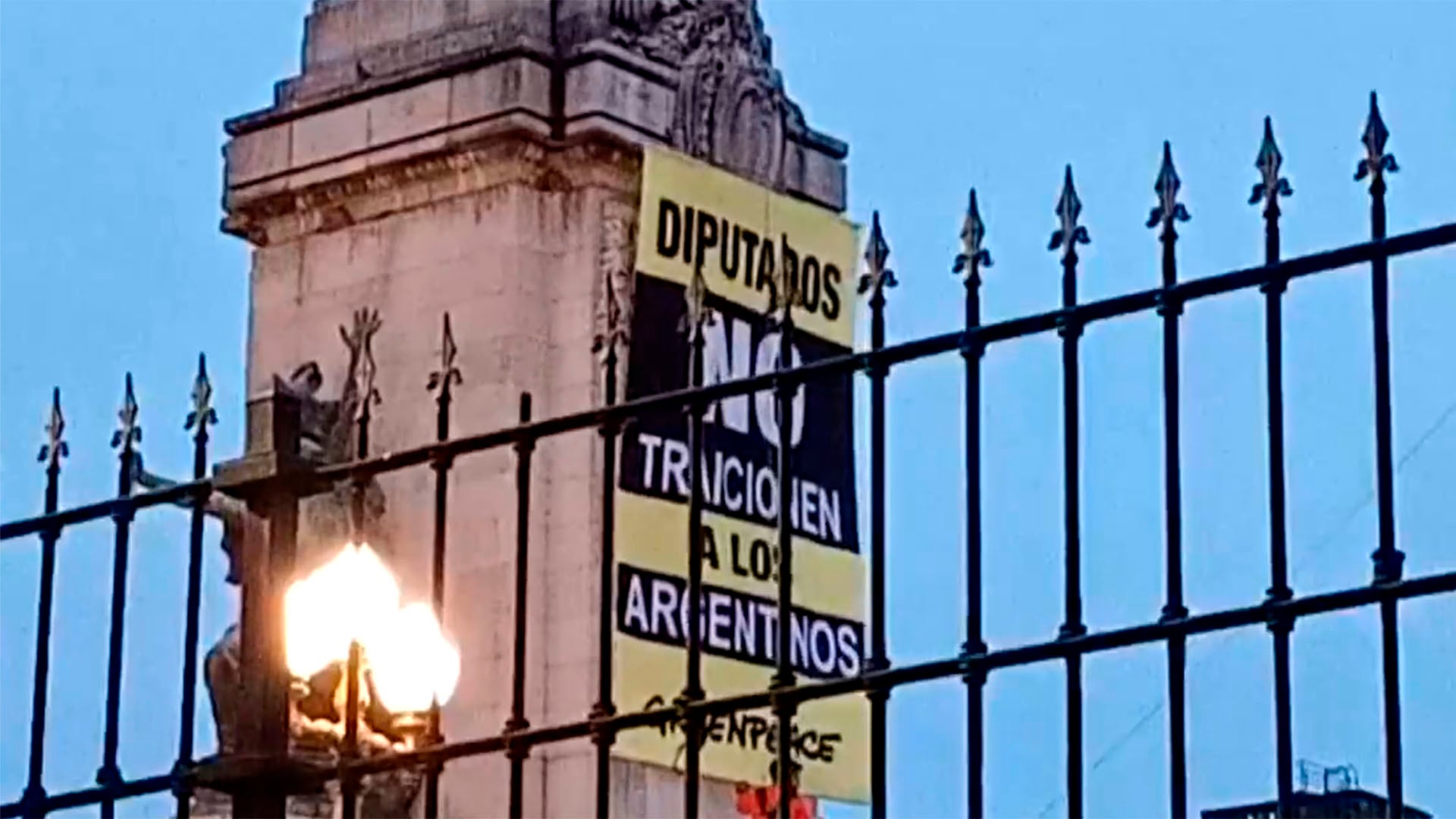 Activistas de Greenpeace cuelgan una pancarta en el Congreso Nacional exigiendo a los diputados que no traicionen la Ley de Glaciares, vista parcial tras una reja ornamental.