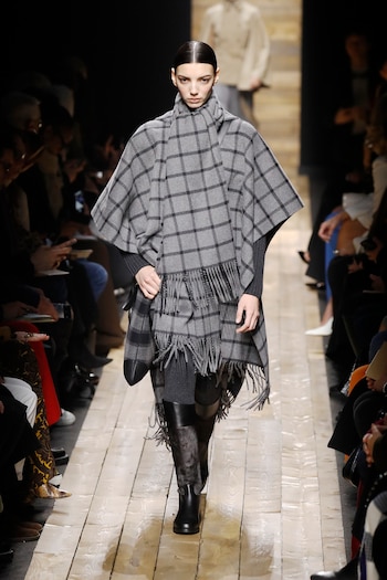 El diseñador estadounidense presentó su nueva temporada donde los cuadros fueron los protagonistas. En pasarela, un look total gris de poncho y maxi bufanda con detalles de flecos. En sus pies botas y medias