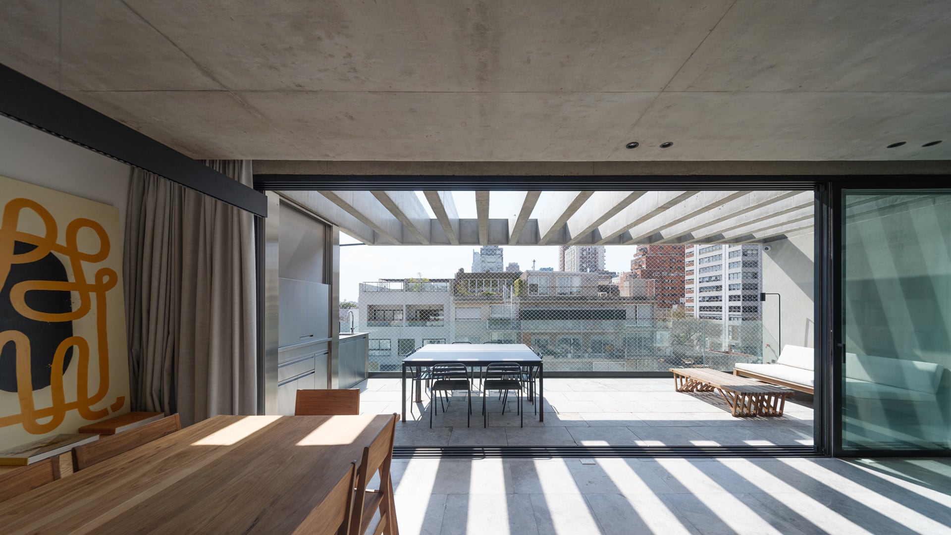 El ventanal de piso a techo completamente abatible integra el estar y el balcón, eliminando la frontera entre interior y exterior