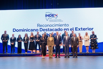 Luis Abinader y cuatro personas posan en un escenario mientras entregan un trofeo a una mujer frente a una pantalla digital azul