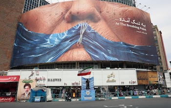 Un hombre sostiene la bandera nacional de Irán delante de una gran valla publicitaria antiestadounidense con un montaje del presidente de Estados Unidos Donald Trump y el estrecho de Ormuz, el pasado jueves 28 de mayo en la plaza Valiasr de Teherán, Irán (EFE)