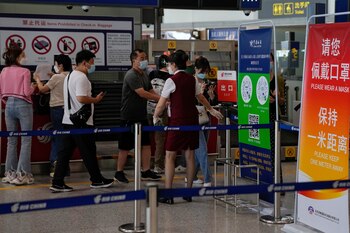 ARCHIVO - Una trabajadora aérea pide a los viajeros que declaren su información de salud tras facturar en el mostrador de vuelos internacionales en el aeropuerto internacional Capital Beijing, en Beijing, el 24 de agosto de 2022. (AP Foto/Andy Wong, Archivo)
