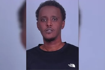Retrato de frente de un hombre con cabello corto y camiseta negra sobre un fondo liso de color claro