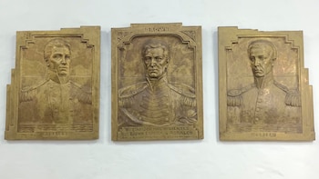 Tres placas de bronce en relieve que representan bustos de hombres con uniformes militares, con los nombres Brown, Rosales y Espora inscritos