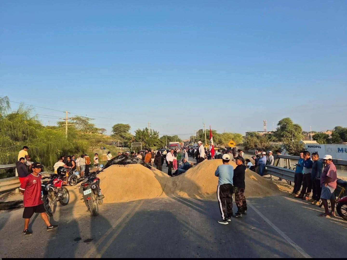 Productores agrarios de Piura bloquean una carretera con montículos de grano y tierra, exigiendo precios justos para sus productos y medidas urgentes del Gobierno central para el sector agrícola.