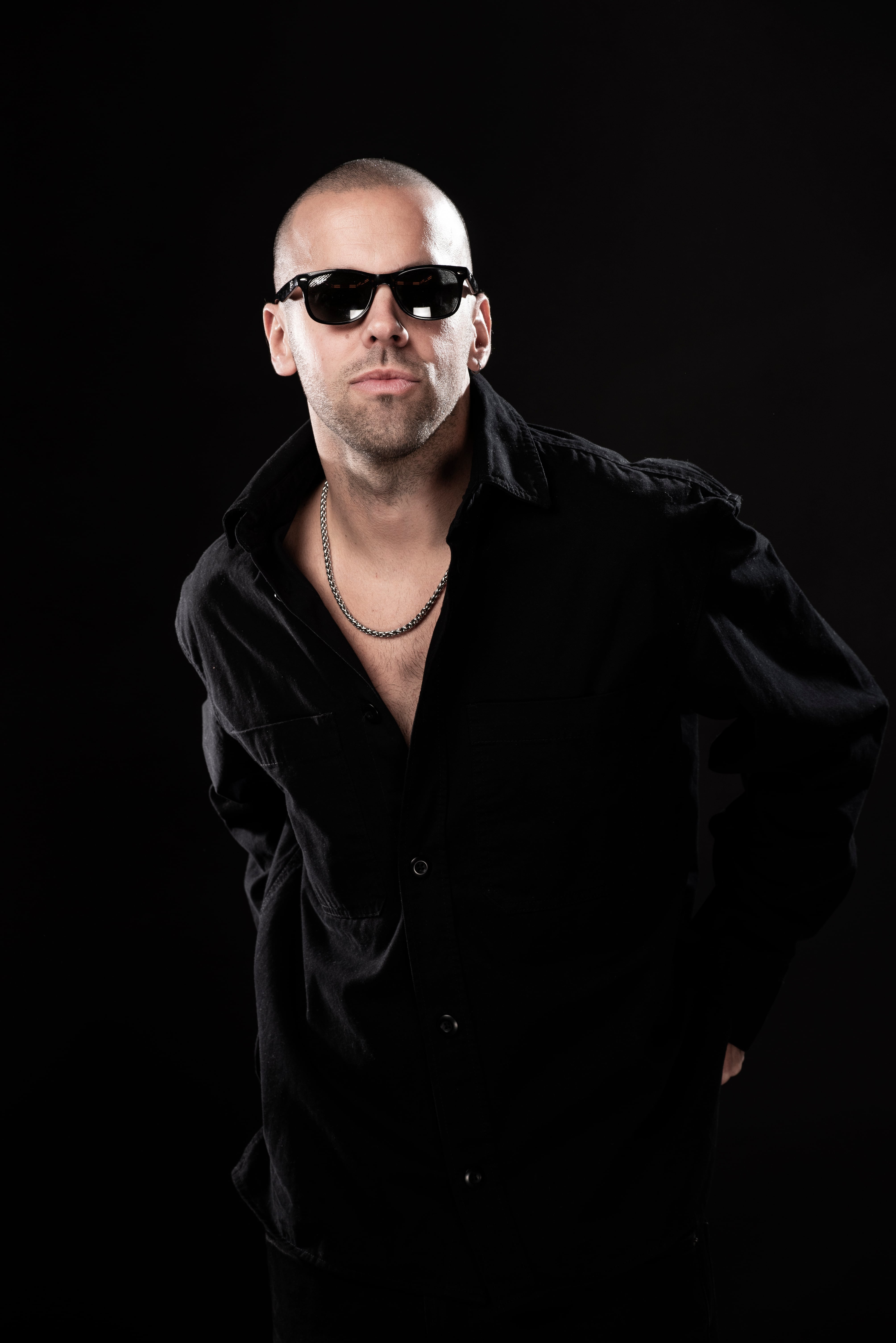 Mati Napp posa con gafas de sol y camisa oscura con el cuello abierto, mostrando una cadena plateada.