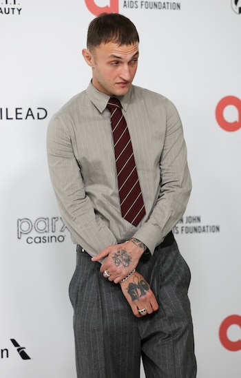 Anwar Hadid combina una camisa gris claro a rayas finas con una corbata burdeos y un pantalón amplio gris oscuro, y deja que los anillos plateados definan el contraste dentro de la formalidad (REUTERS/Jeenah Moon)