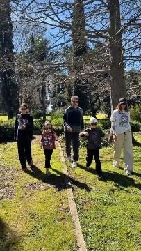 Paula Chaves y Pedro Alfonso caminan junto a sus tres hijos en un espacio verde rodeado de árboles.