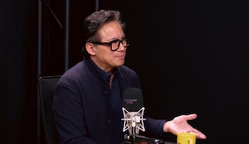 El Dr. William Li, un hombre asiático de mediana edad con gafas de montura gruesa y chaqueta oscura, habla frente a un micrófono negro en un estudio