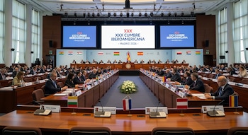 Amplio salón de conferencias con delegados sentados en mesas en forma de U. Tres pantallas grandes muestran "XXX CUMBRE IBEROAMERICANA - MADRID 2026 -".