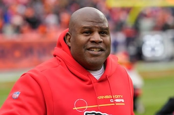 Primer plano de un hombre calvo con barba incipiente, vistiendo una sudadera con capucha roja con el logo de la NFL y texto 'Kansas City Chiefs'