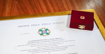 Un diploma oficial de la "Ordine della Stella d'Italia" en un marco dorado y una pequeña caja de terciopelo rojo con un emblema dorado en la parte superior