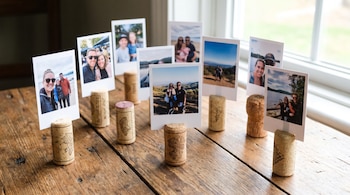 Varias fotografías de estilo instantáneo insertadas en corchos de vino colocados sobre una mesa de madera.
