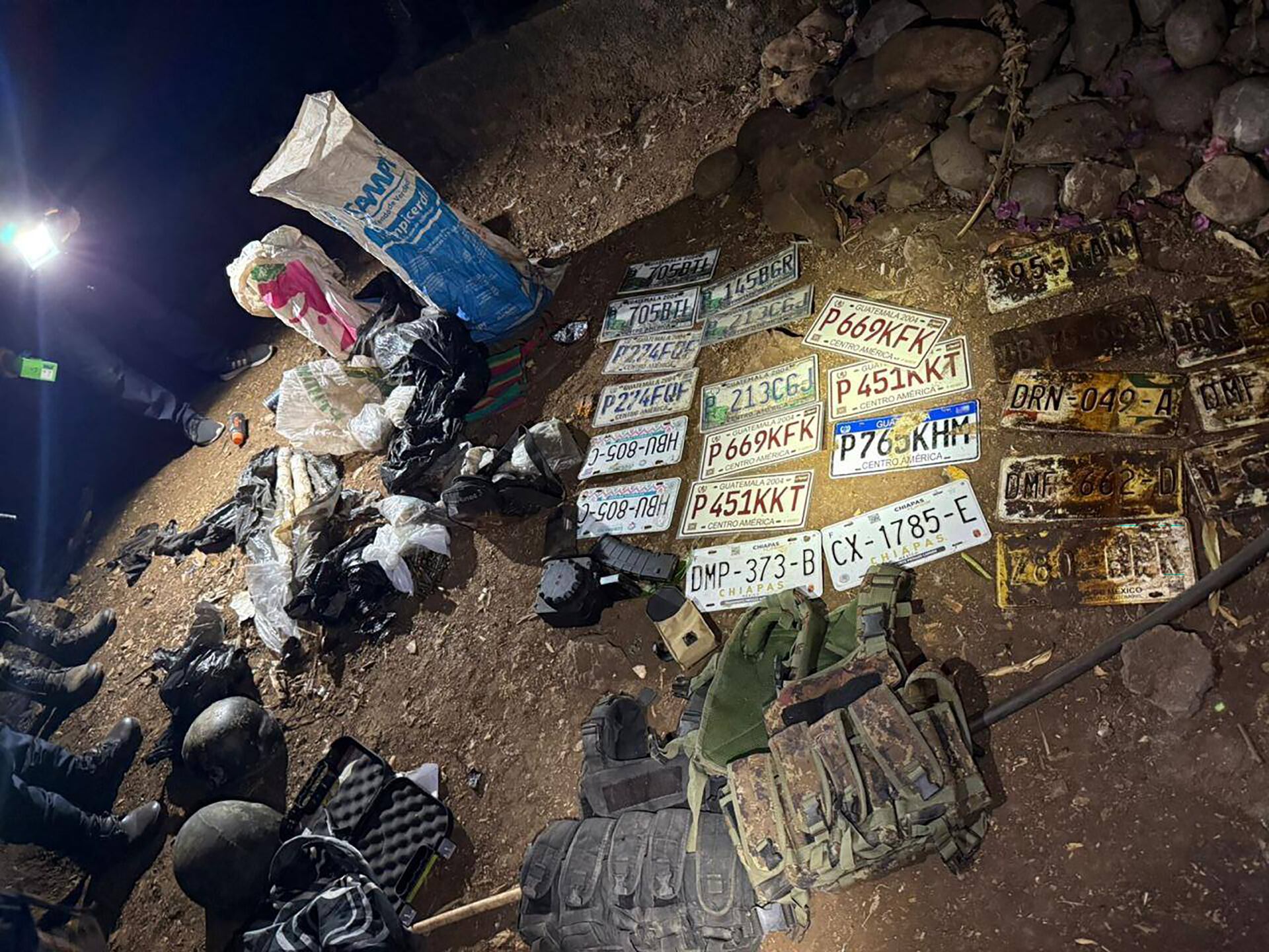 Autoridades incautan un gran número de placas de vehículos, equipo táctico y paquetes con sustancias ilícitas durante un operativo nocturno en una zona clandestina. (Ministerio Público de Guatemala)