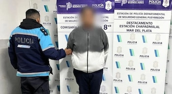 Un policía de espaldas sostiene del brazo a una persona con el rostro difuminado frente a un cartel de la Policía de la Provincia de Buenos Aires