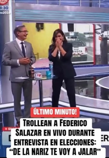 Dos presentadores de televisión ríen en un estudio. Un hombre con traje sonríe y una mujer se cubre la boca, ambos reaccionando en vivo durante una transmisión