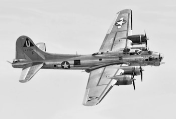 Fotografía en blanco y negro de un avión B-17 Flying Fortress en vuelo con insignias de Estados Unidos en la estructura