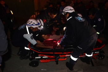 Un grupo de rescatistas con cascos y linternas frontales asiste a una persona en una camilla de emergencia en la oscuridad