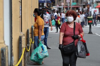 Mujeres llevan bolsas tras realizar