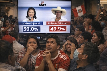 Peruanos miran con angustia una pantalla que muestra resultados de ONPE: Keiko Fujimori 50.0% y Roberto Sánchez 49.9%. Hay una bandera peruana.