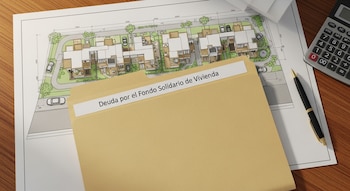 Carpeta de color ocre con etiqueta "Deuda por el Fondo Solidario de Vivienda" sobre plano arquitectónico de casas, calculadora y bolígrafo en escritorio.