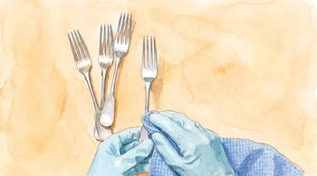 Manos con guantes sujetan un tenedor y lo secan con un paño; tres tenedores apilados a la izquierda sobre un fondo con textura acuarela.