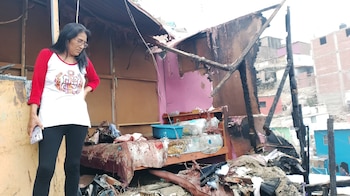 Una mujer damnificada mira los restos de su vivienda calcinada